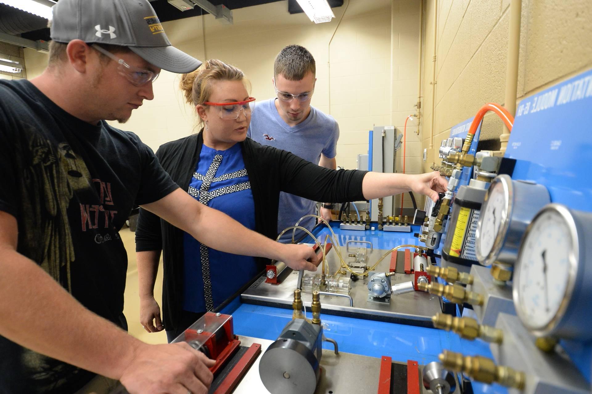 An engineering professor showing her students how to use a machine