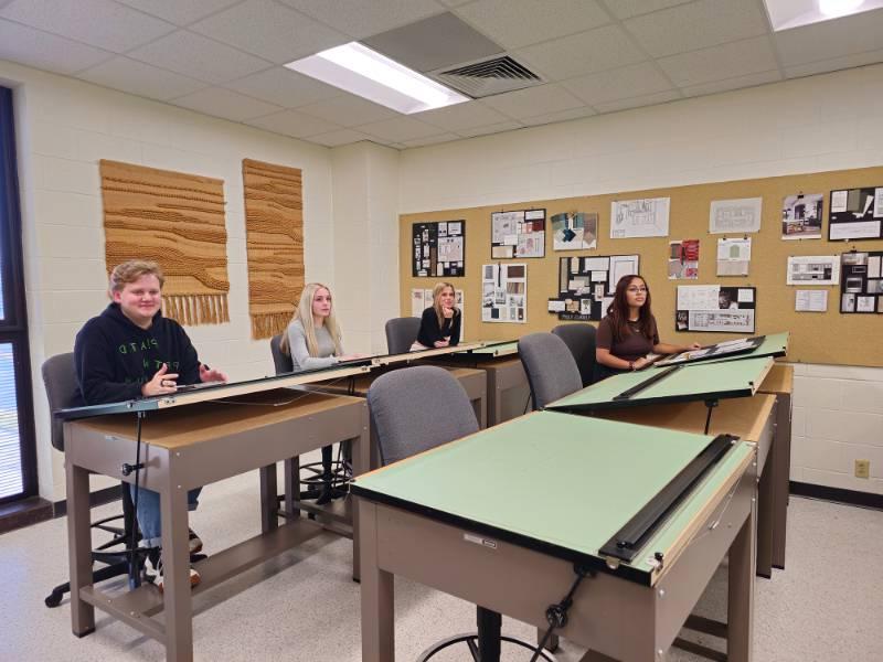 Students in class at the design table with materials