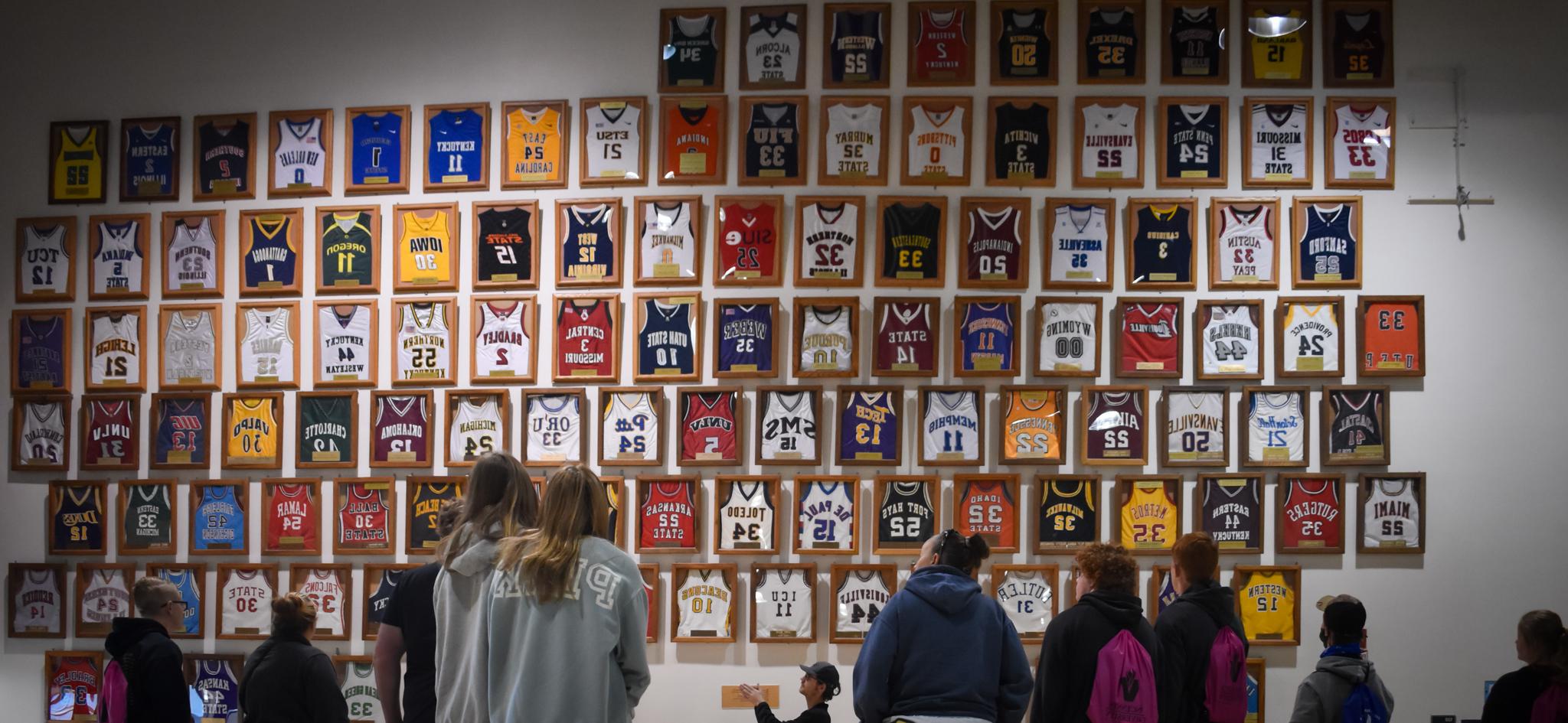 Framed basketball jerseys hanging on a wall in the P.E. complex