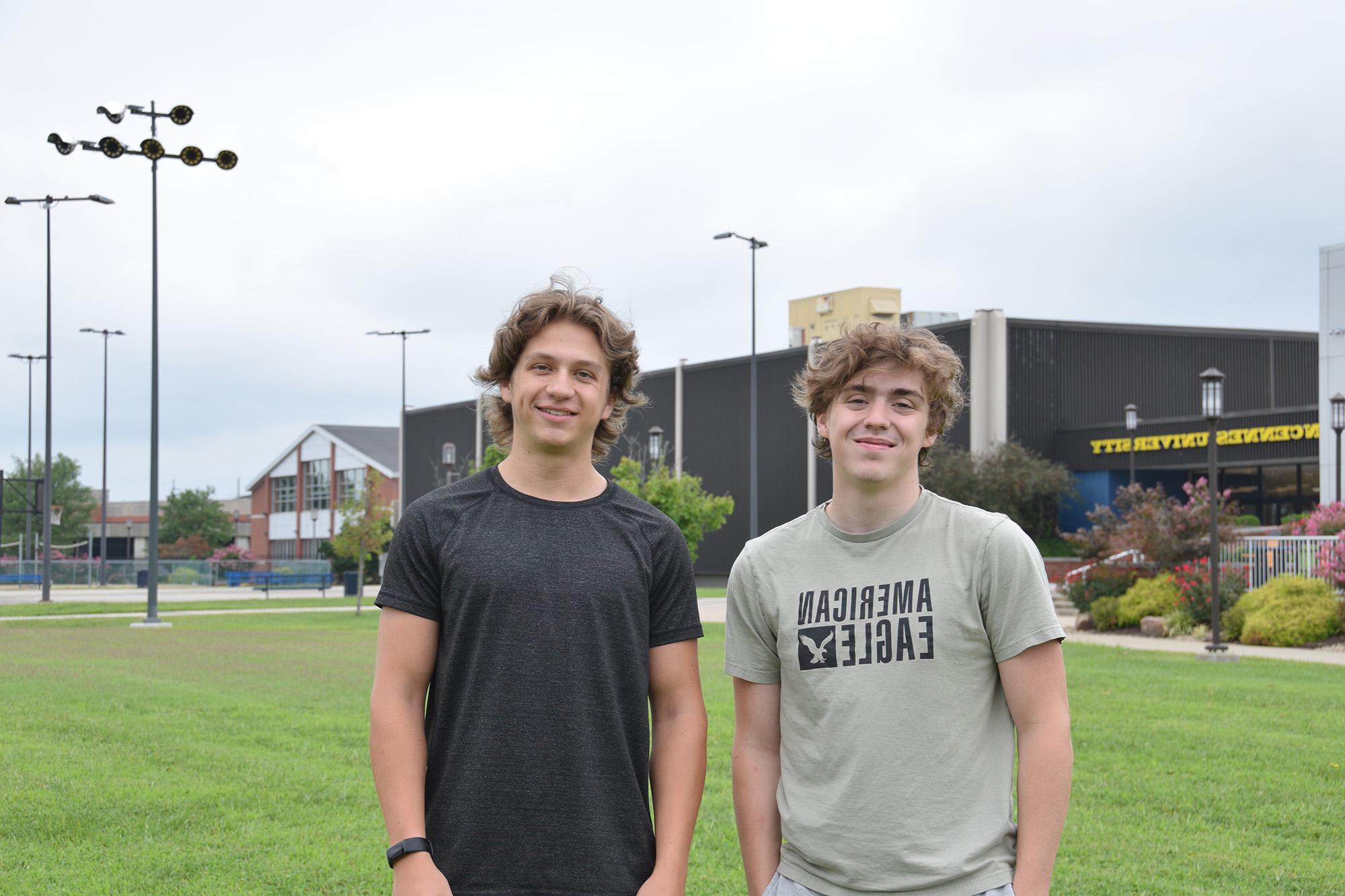 Two male students standing in front of the physical education complex